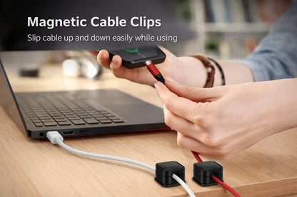 Magnetic cable clips holding charging cables on a desk next to a laptop